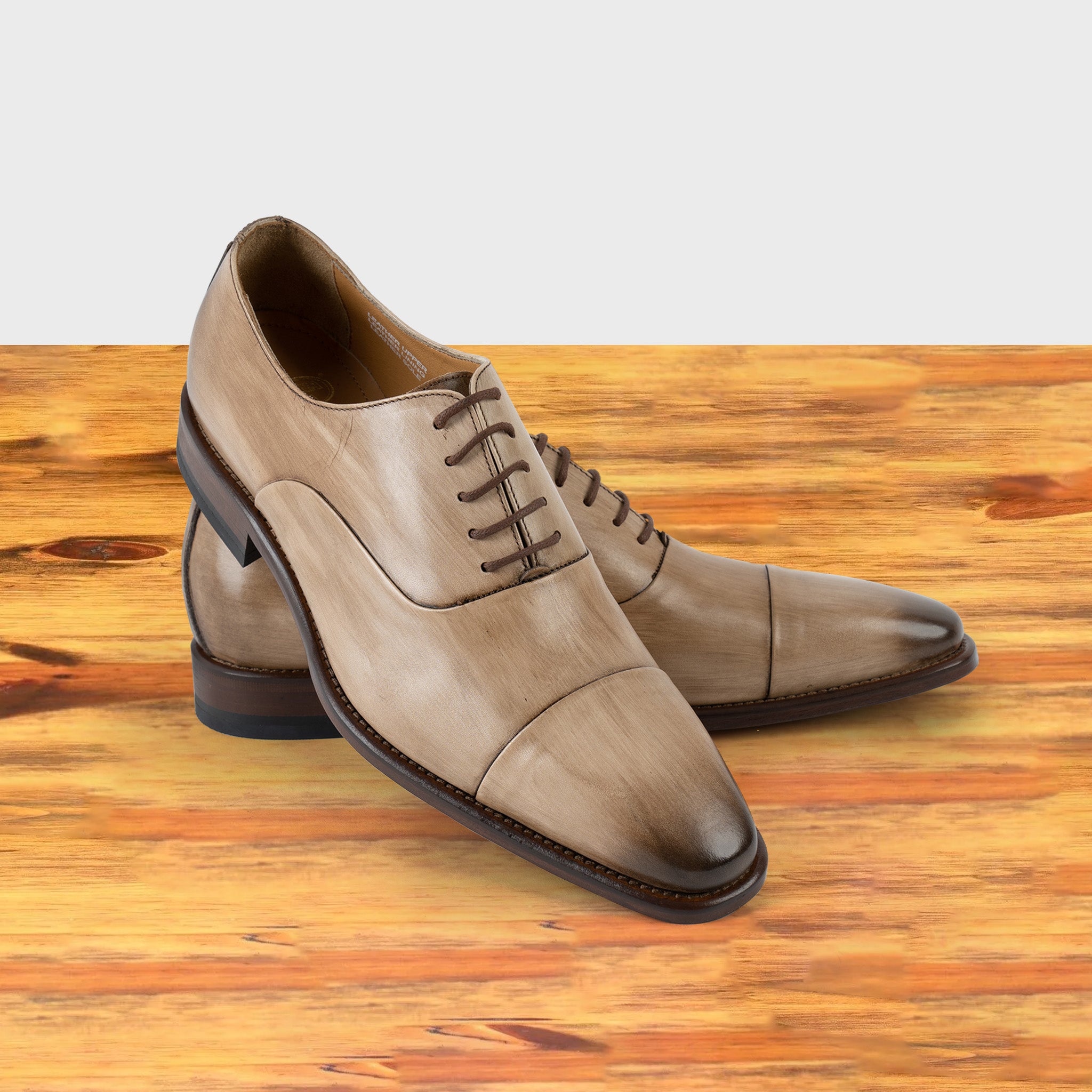 Straw leather shoe on a wooden surface with a light gray background