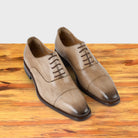 Straw leather shoe on a wooden surface with a light gray background
