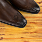  Brown leather shoe on a wooden surface