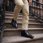 Person wearing a navy blazer, striped sweater, beige pants, and black shoes on a city street.