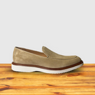 Cream loafer shoe on a wooden surface with a light gray background