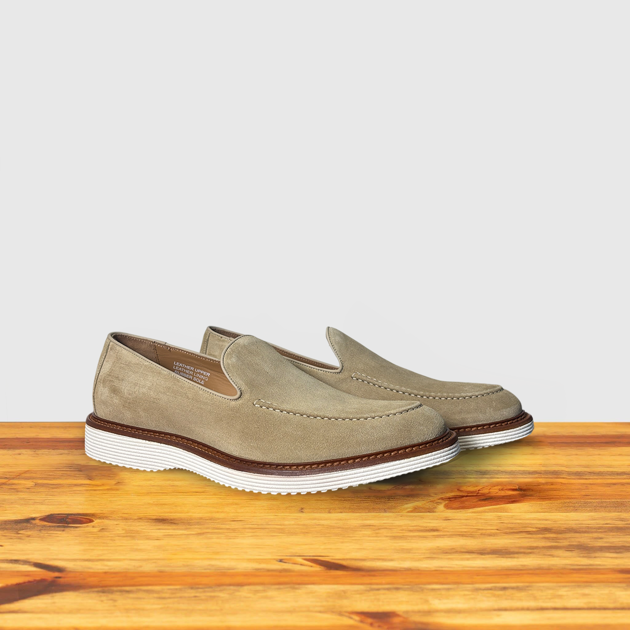 A Pair of Cream loafer shoe on a wooden surface with a light gray background