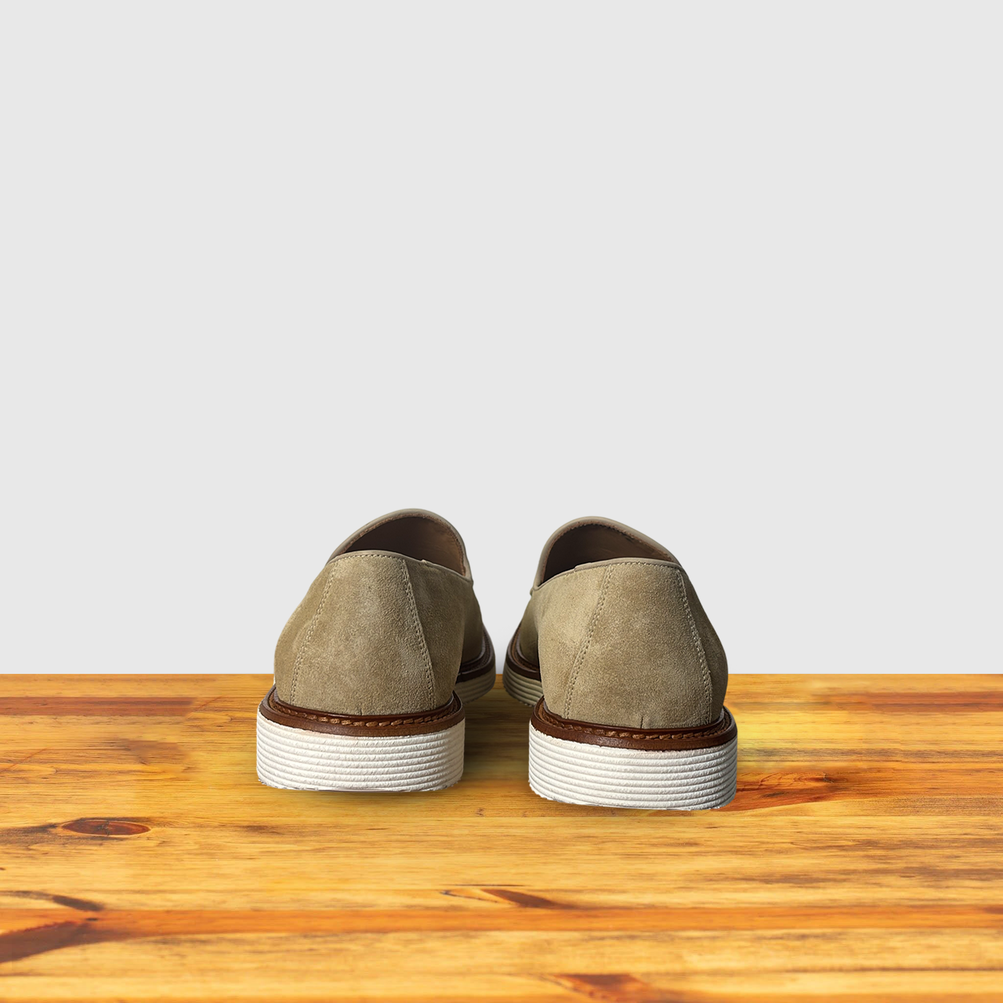 A Pair of Cream loafer shoe on a wooden surface with a light gray background
