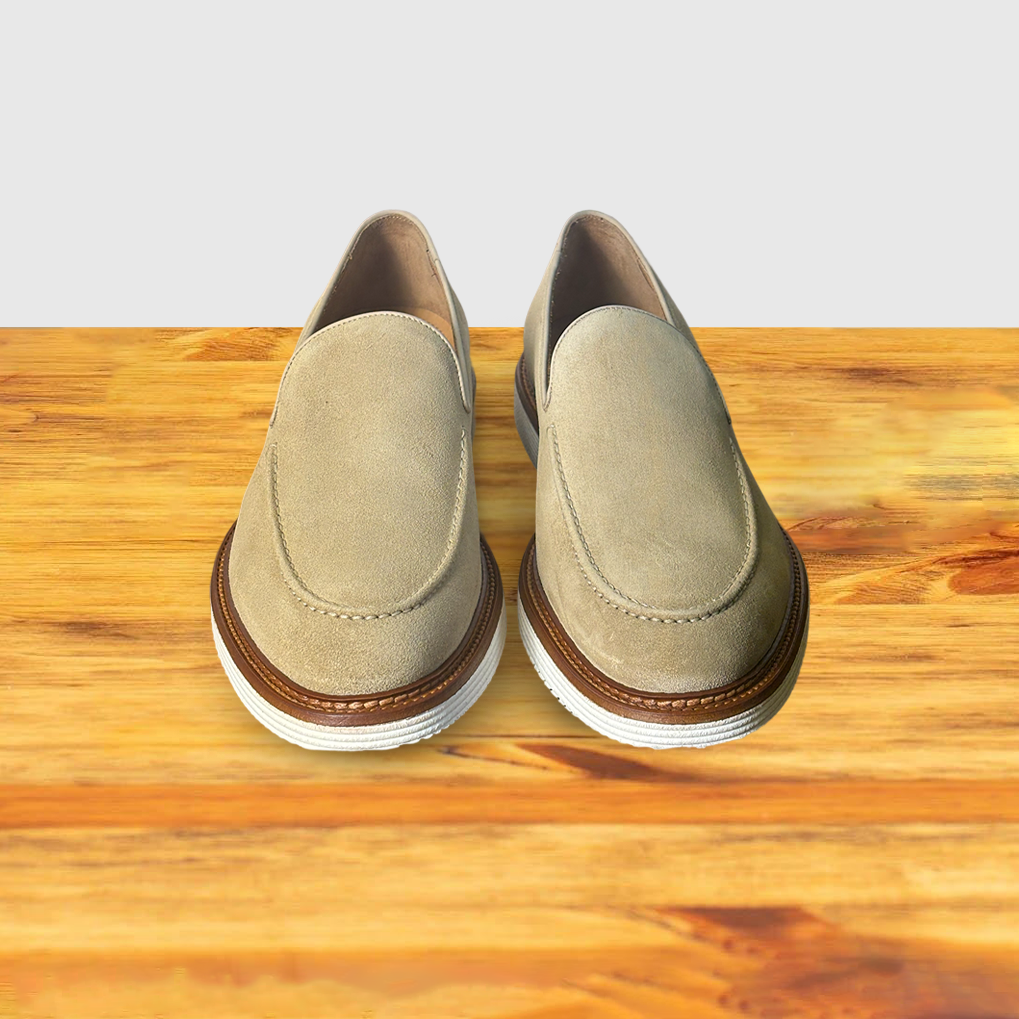 A Pair of Cream loafer shoe on a wooden surface with a light gray background
