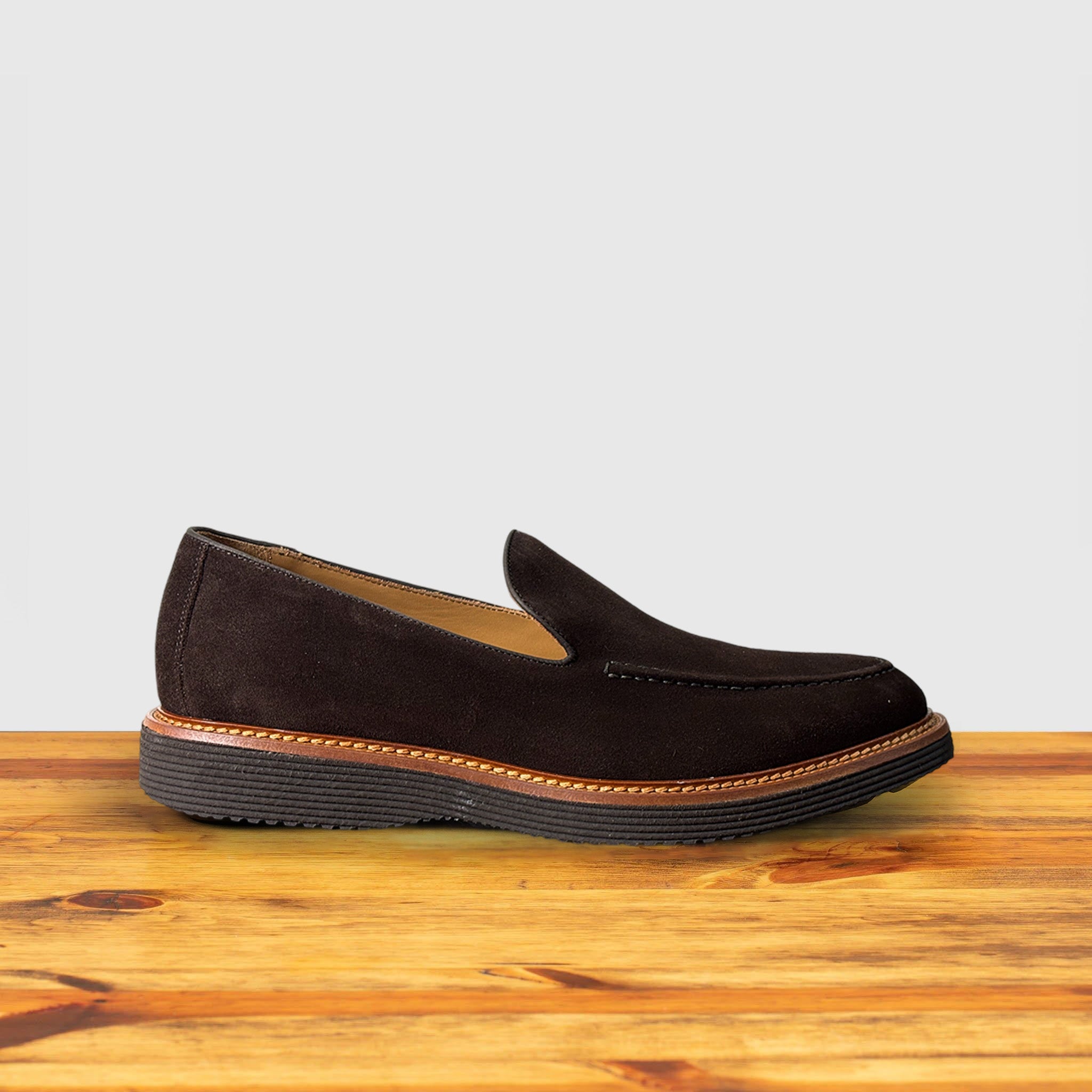 A Brown Venetian loafer with a rubber sole positioned on a wooden surface.