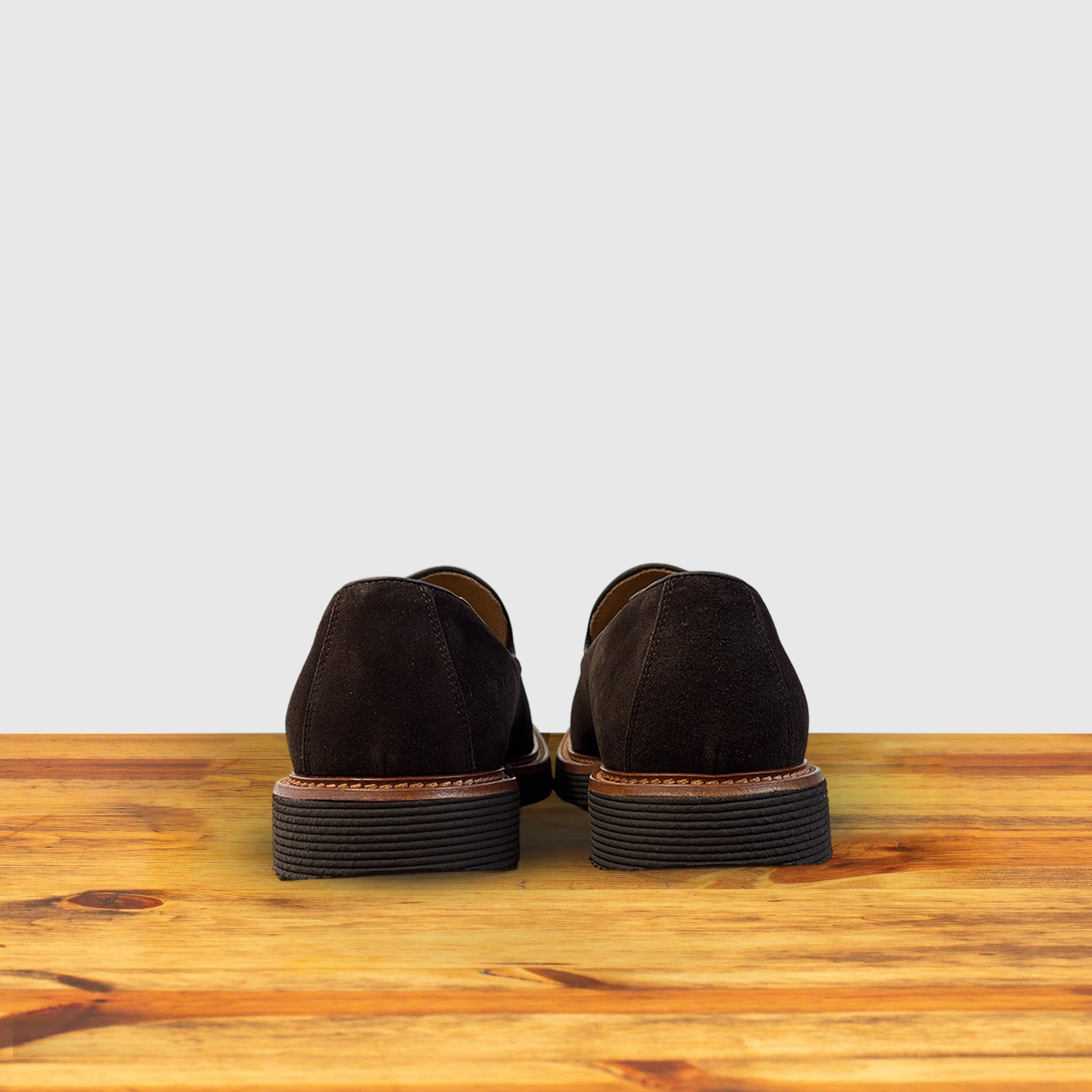 A Pair of Brown Venetian loafer with a rubber sole positioned on a wooden surface.