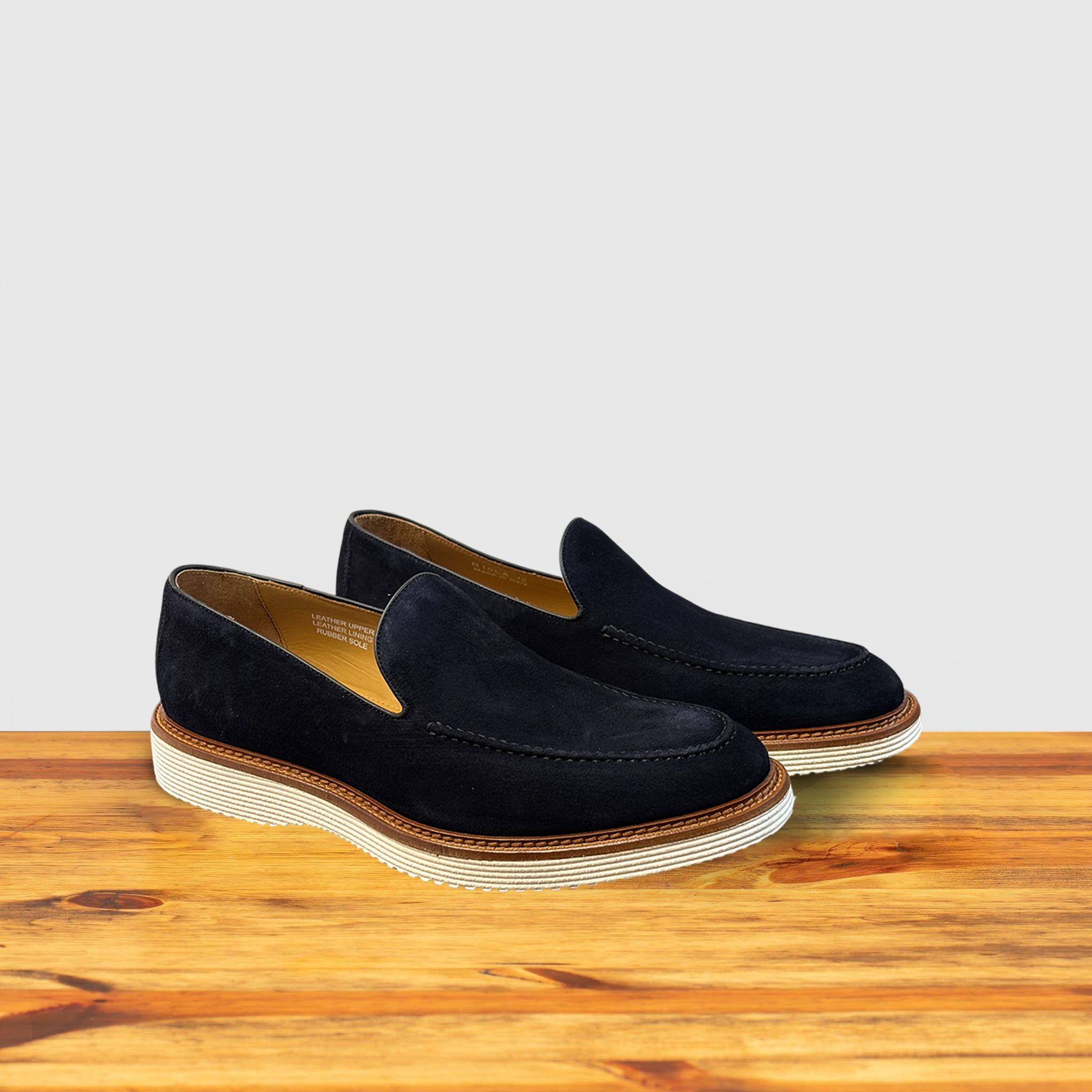 Pair of navy blue loafers on a wooden surface with a light gray background