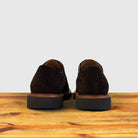 A Pair of brown suede wingtip shoe with a rubber sole, displayed on a wooden surface.
