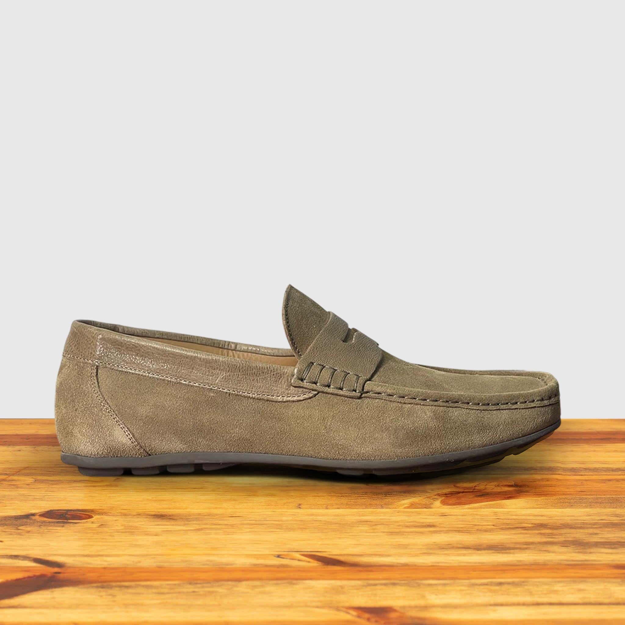 A Rope color suede penny loafer, displayed on a wooden surface.