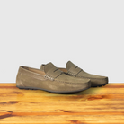 A pair of Rope color suede penny loafer, displayed on a wooden surface.