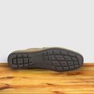 Outsole of Rope color suede penny loafer, displayed on a wooden surface.