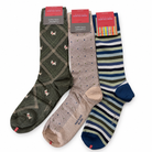 Three pairs of Marcoliani dress socks: olive green argyle with white dog motifs, beige with small blue and green squares, and blue, green, and white stripes.