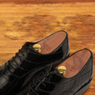 A Pair of Black crocodile leather shoe on a wooden surface