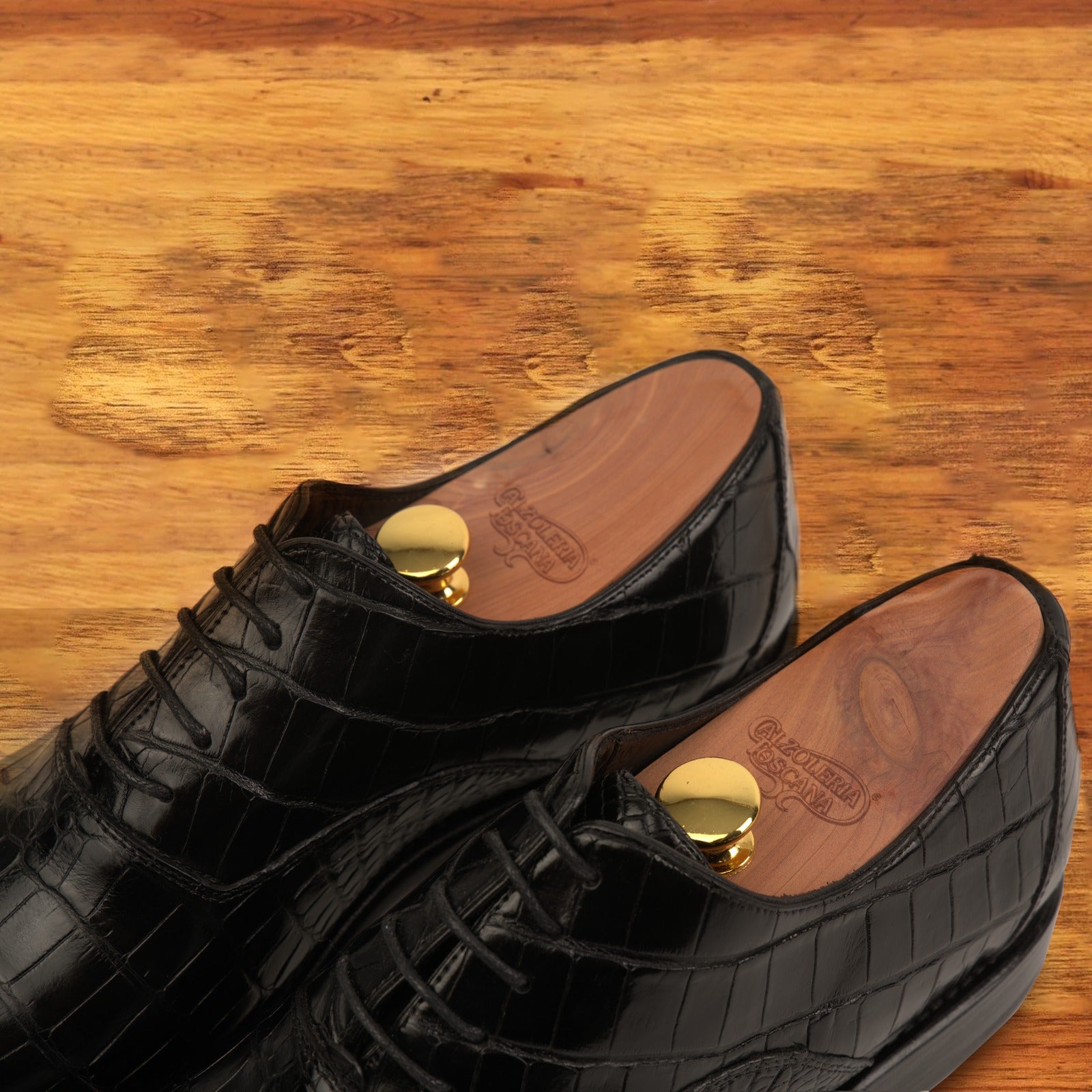 A Pair of Black crocodile leather shoe on a wooden surface