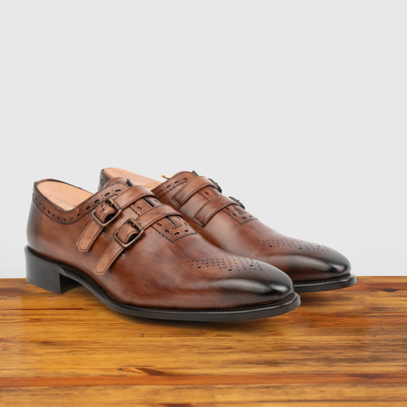 A Pair of Brown leather shoe with double buckles on a wooden surface