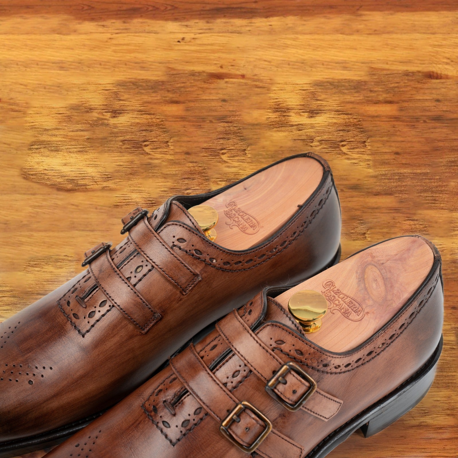 Brown leather shoe with double buckles on a wooden surface