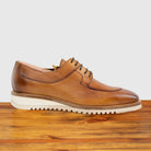 Brown leather shoe on a wooden surface with a light gray background