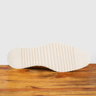 Outsole of Brown leather shoe on a wooden surface with a light gray background