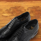  A pair of Black woven dress shoe on a wooden surface