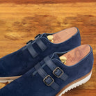A Pair of Navy blue suede shoe with white sole on a wooden surface