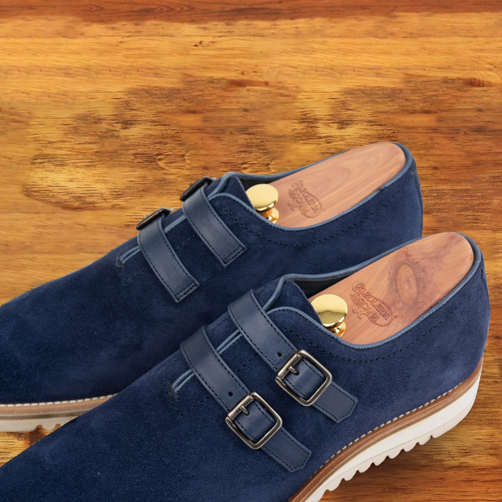 A Pair of Navy blue suede shoe with white sole on a wooden surface