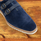 Navy blue suede shoe with white sole on a wooden surface