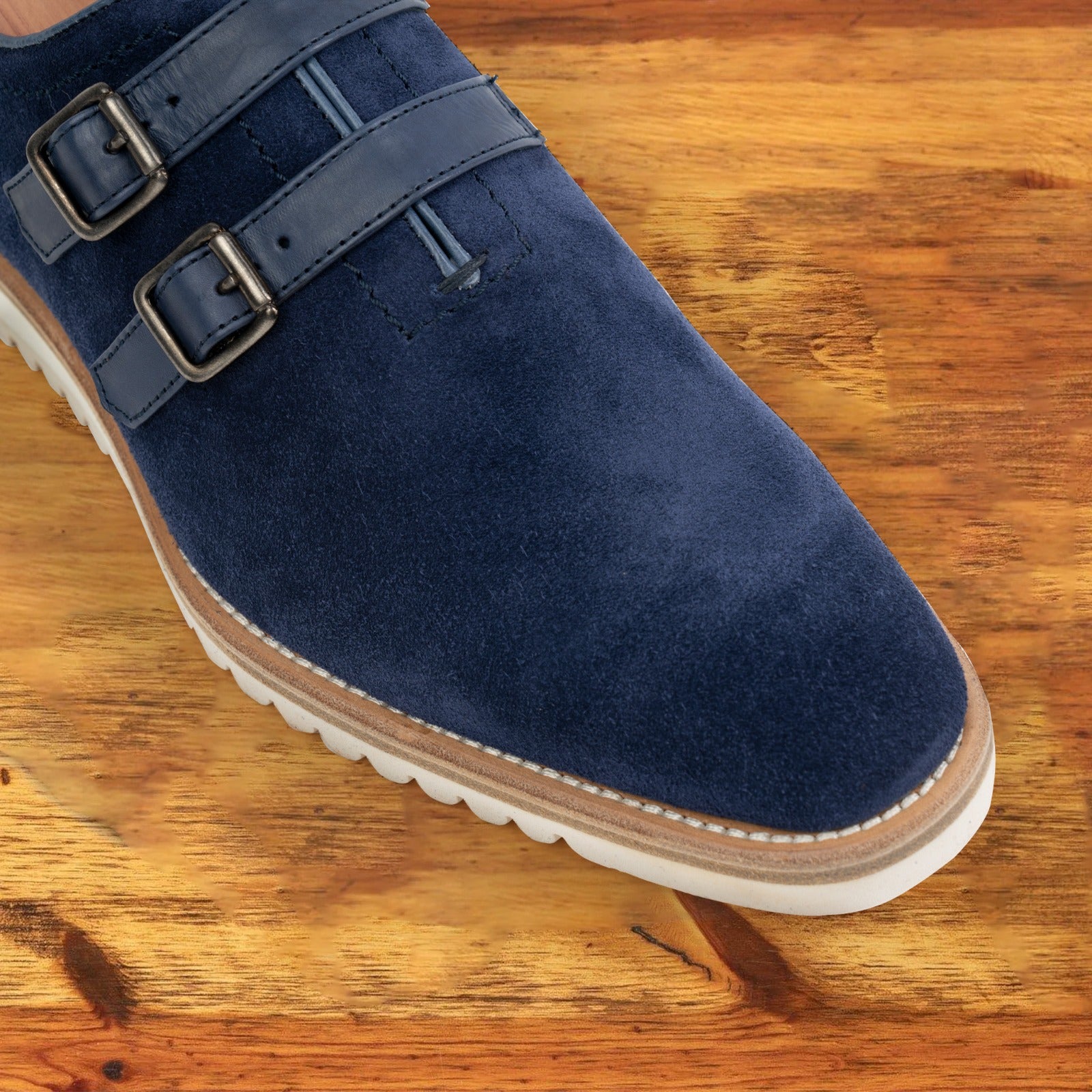 Navy blue suede shoe with white sole on a wooden surface