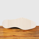Outsole of Navy blue suede shoe with white sole on a wooden surface