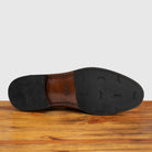 Outsole of Dark Caramel leather loafer on a wooden surface with a light gray background