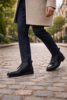 Person wearing black leather shoes on a cobblestone street