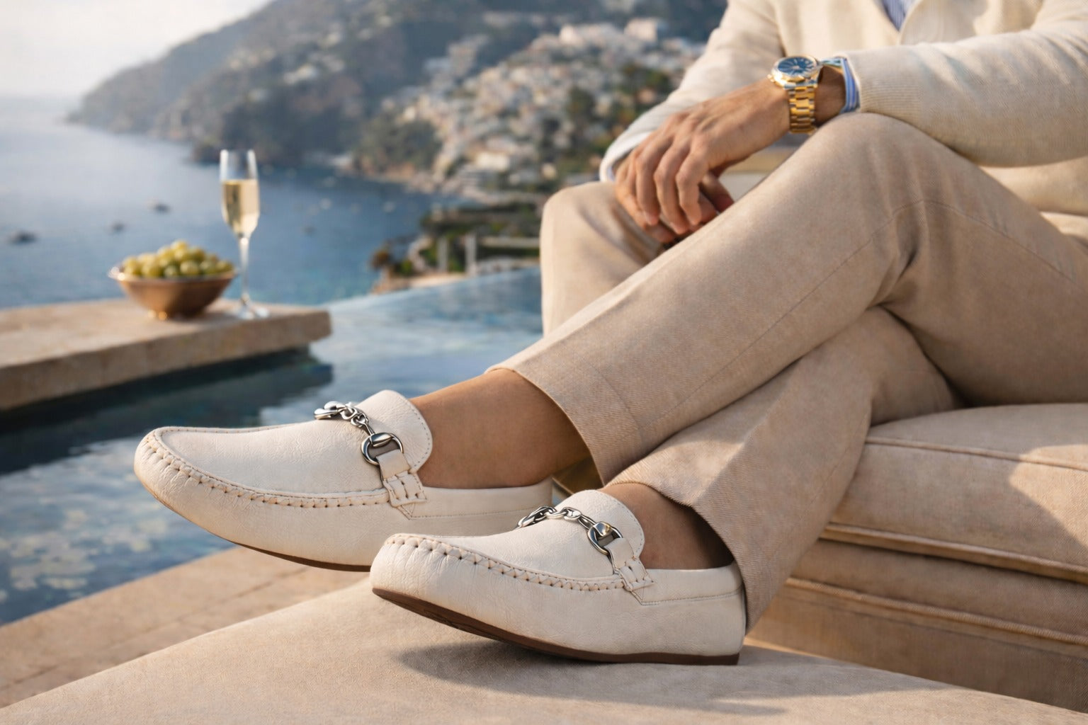 Person wearing white loafers with silver straps by a poolside with scenic background