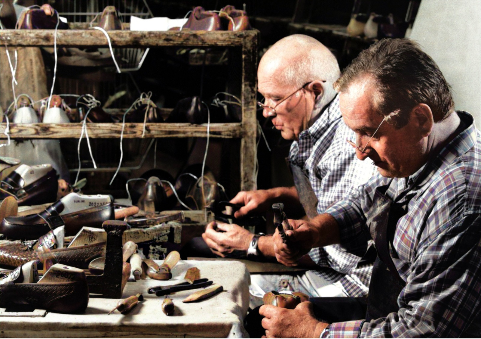 Italian artisan shoemakers hand-assembling leather shoes in a traditional workshop