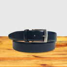 Black leather belt with silver buckle on a wooden surface