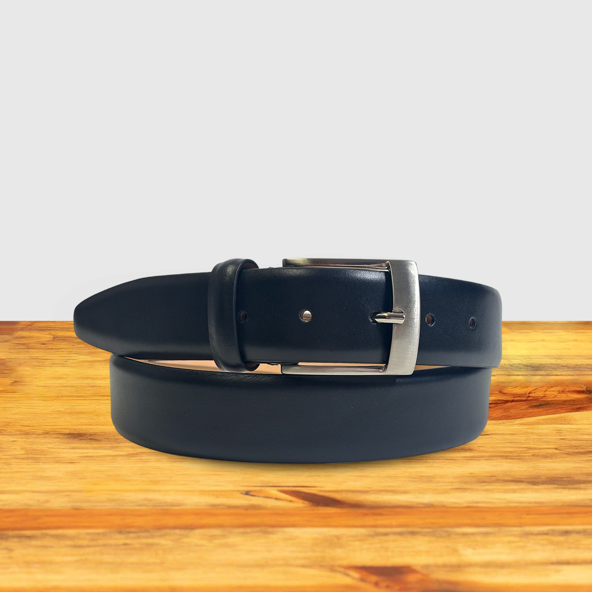 Black leather belt with silver buckle on a wooden surface