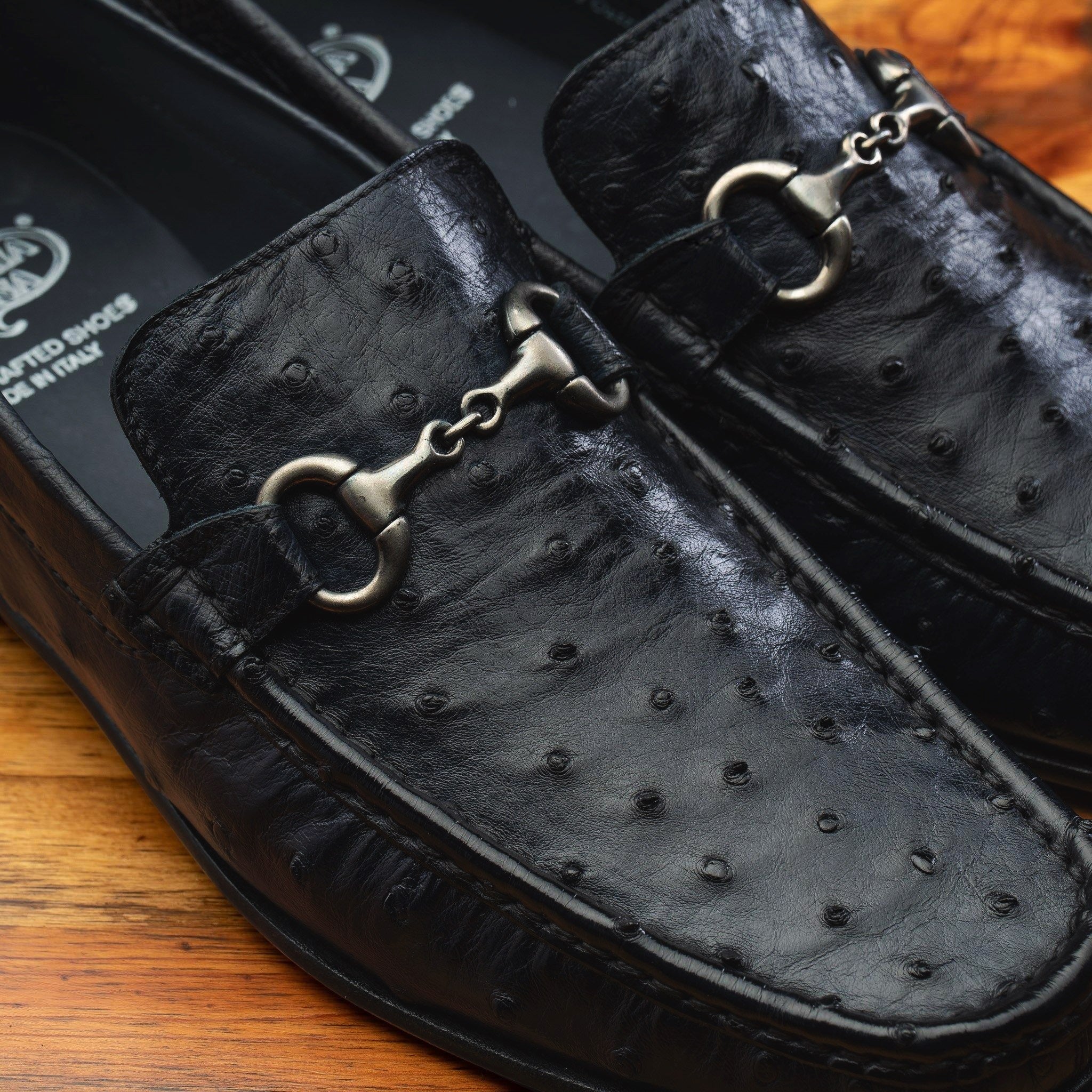 Close view of Black leather loafer on a wooden surface