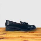 Black loafer shoe on a wooden surface with a light gray background