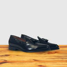 Pair of black loafers on a wooden surface with a light gray background