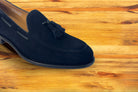 Navy blue loafer with a tassel on a wooden surface