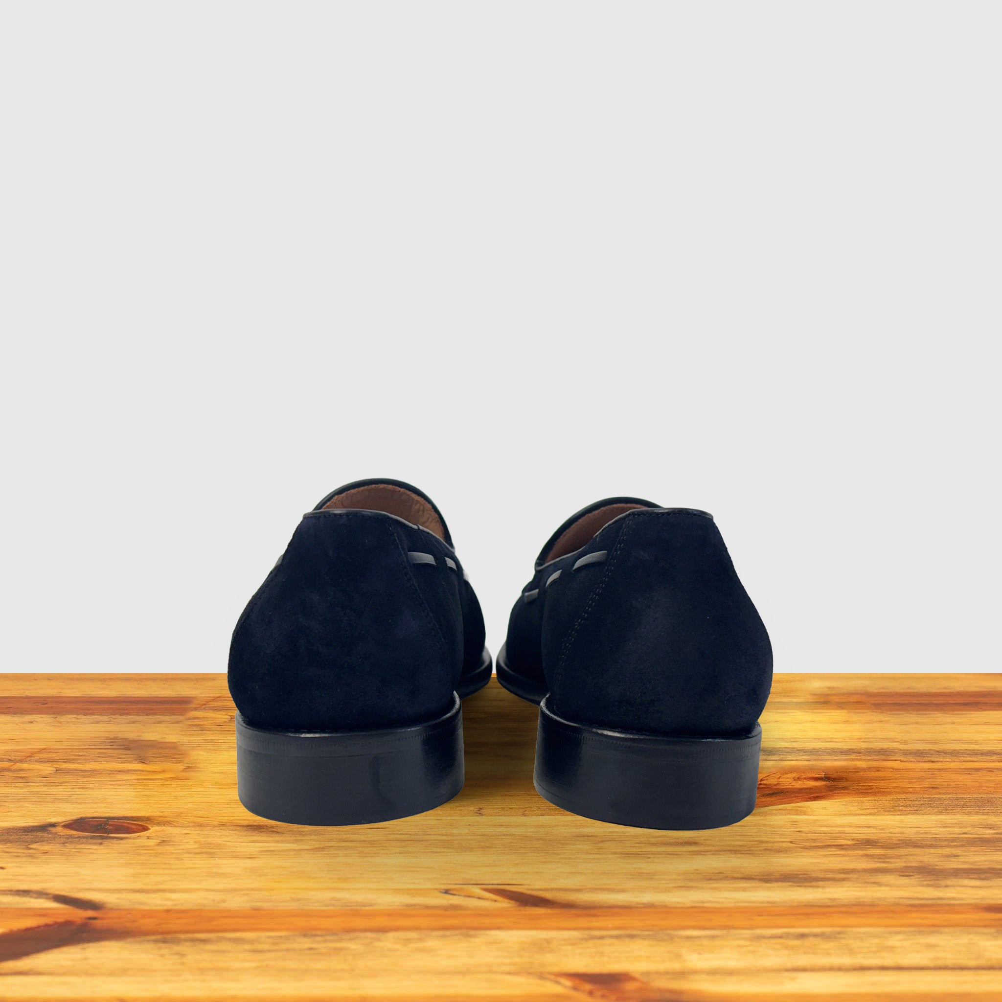 Navy blue loafer with a tassel on a wooden surface