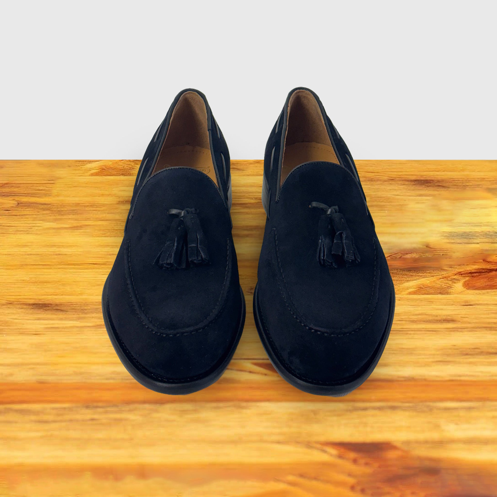  A Pair of Navy blue loafer with a tassel on a wooden surface