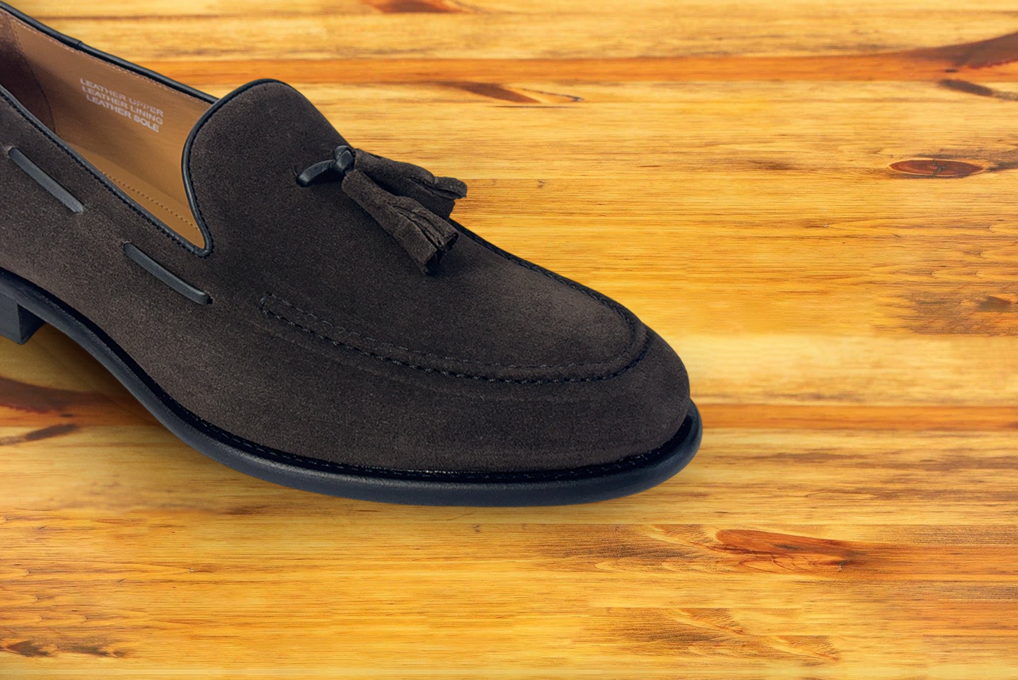 A  Brown color loafer with a tassel  placed on a wooden surface.