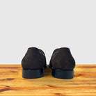 Backside of a Brown loafer placed on a wooden surface.