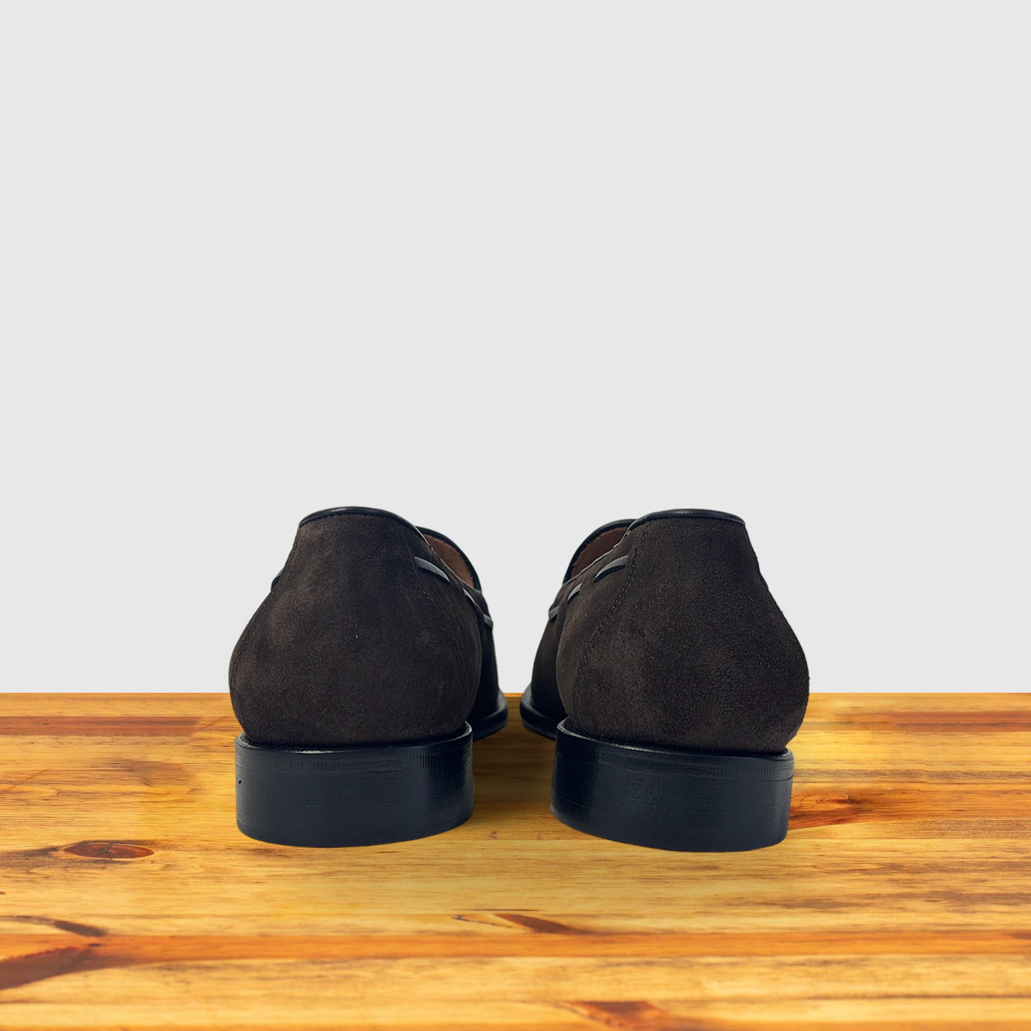 Backside of a Brown loafer placed on a wooden surface.