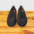 A Pair of Dusty Brown loafer with a tassel placed on a wooden surface.