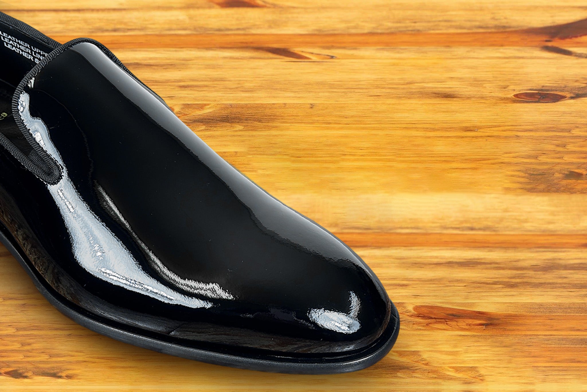 Black patent leather loafer on a wooden surface