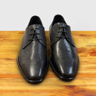 A  Pair of Black leather dress shoe on a wooden surface with a light gray background