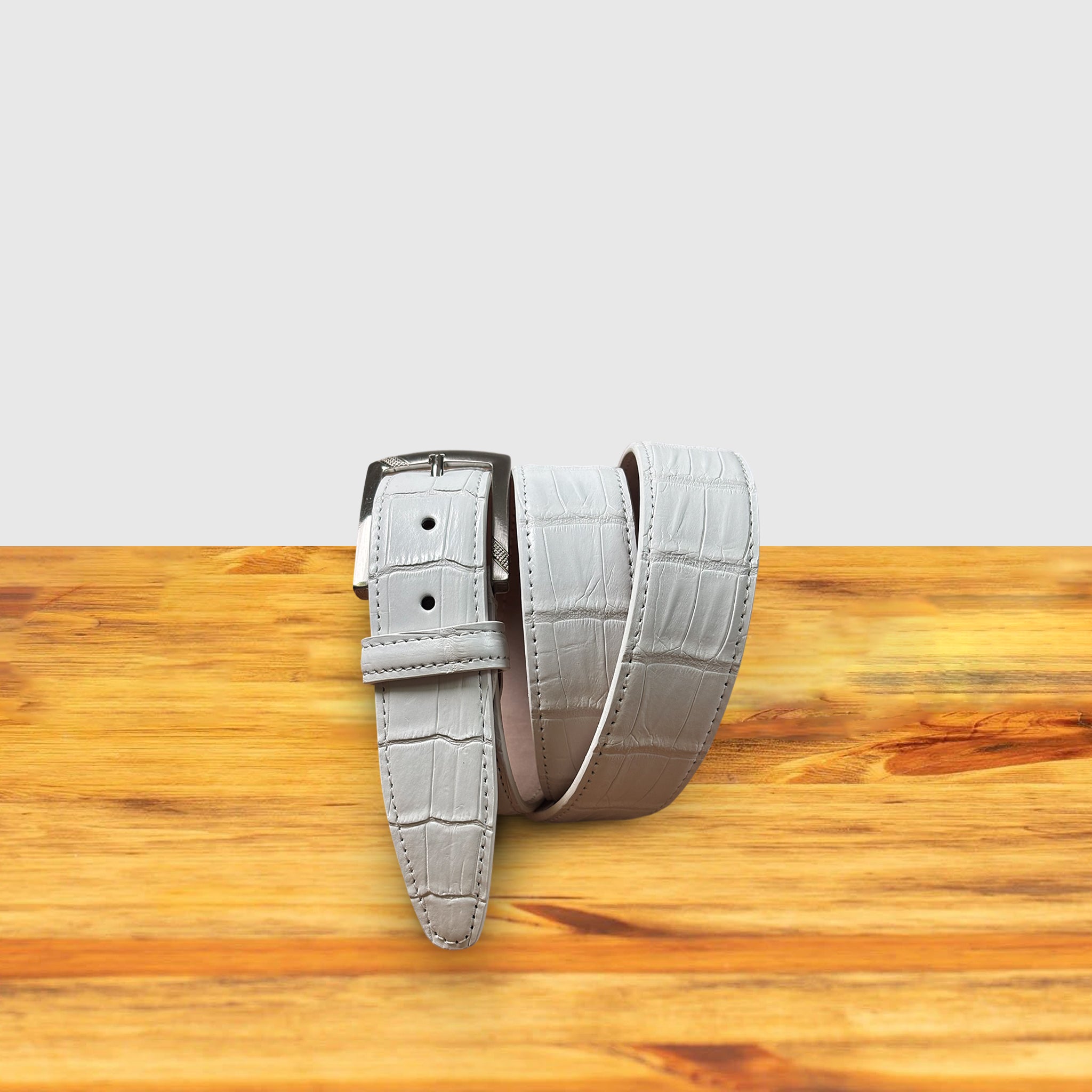 C8099  White Calzoleria Toscana Crocodile Belt on a wooden surface