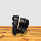 Black leather belt on a wooden surface with a light gray background