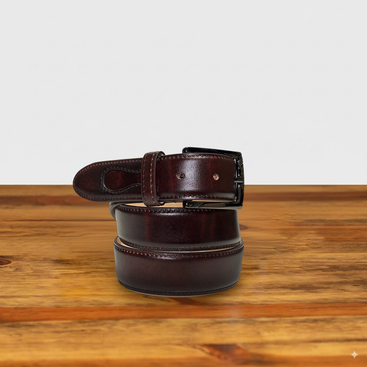 Burgundy leather belt on a wooden surface with a light gray background