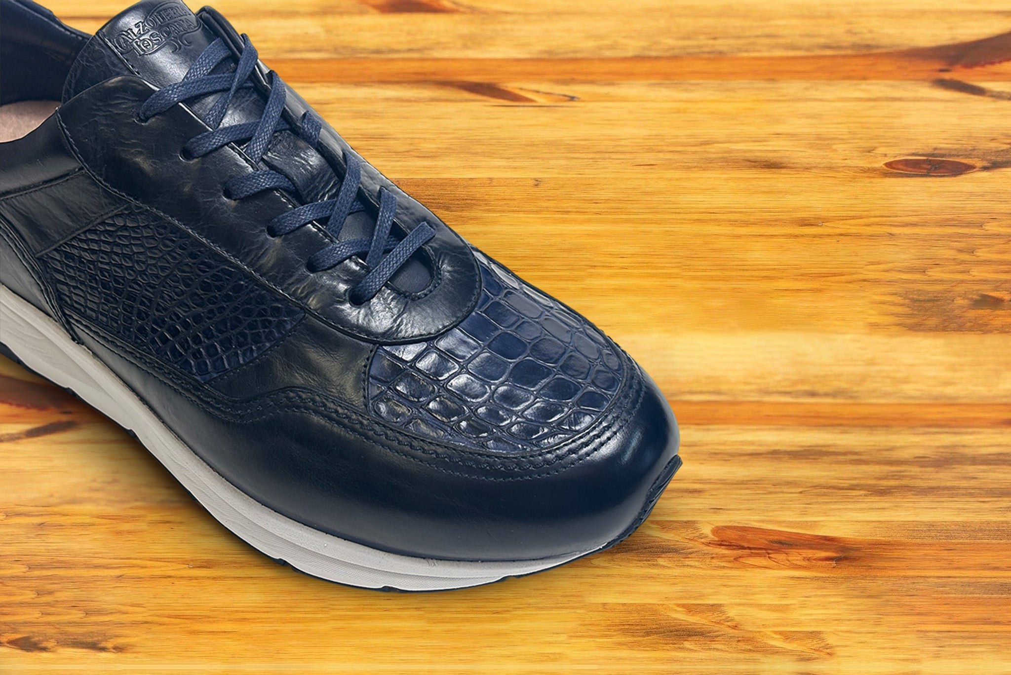 Blue sneaker with a white sole on a wooden surface